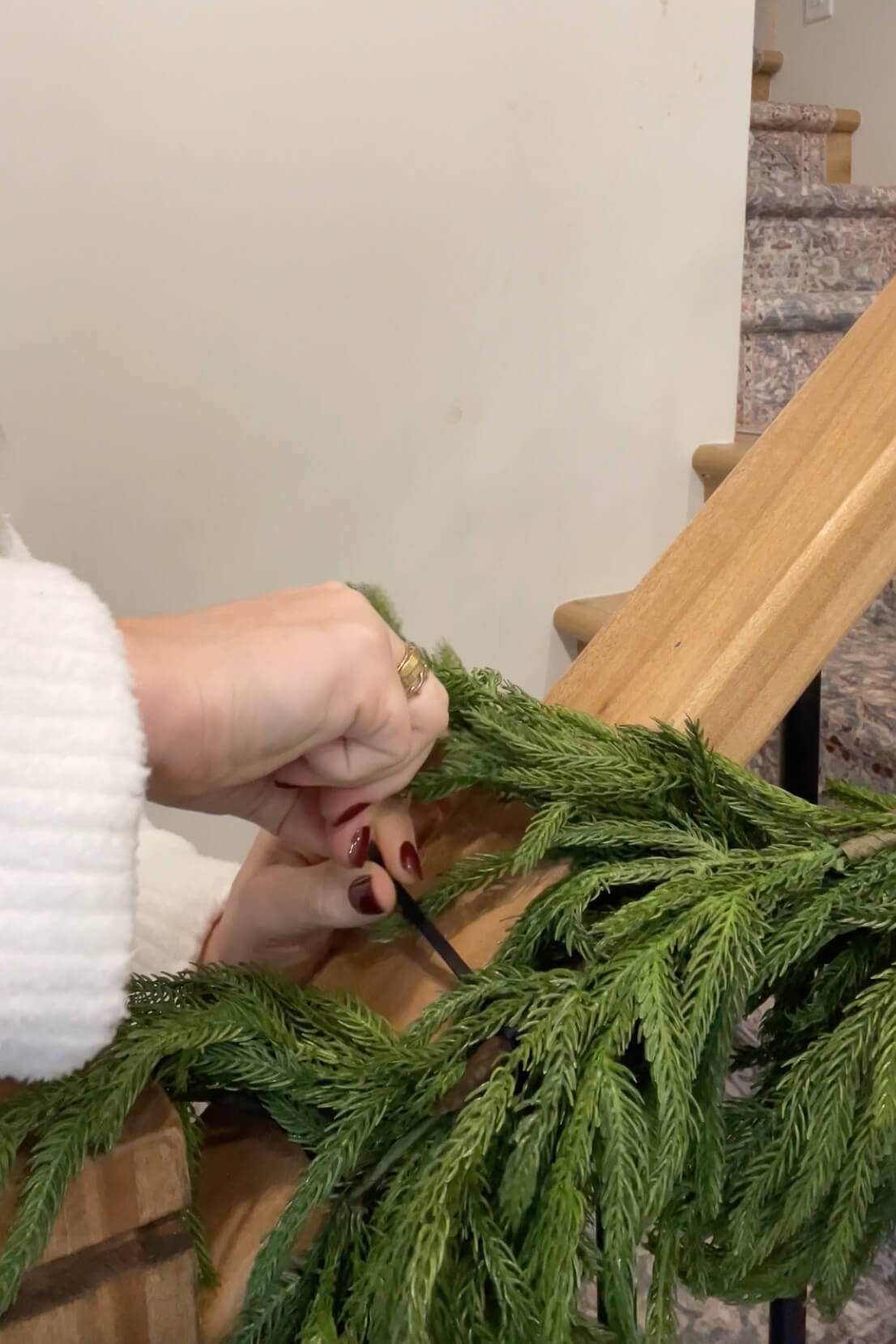 Using zip ties to attach realistic looking pine garland to a stair rail. 